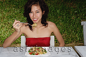 Asia Images Group - Woman sitting in restaurant eating pasta, looking at camera, smiling