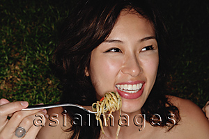 Asia Images Group - Woman holding fork full of pasta, smiling