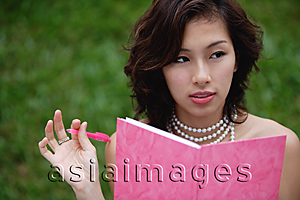 Asia Images Group - Woman wearing necklace and writing in pink journal
