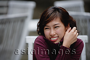 Asia Images Group - woman sitting at an outdoor cafe, wearing sweater, smiling