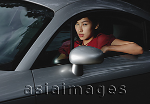 Asia Images Group - Woman driving car, looking out window at camera