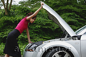 Asia Images Group - woman checking engine of car, hood up, on side of road