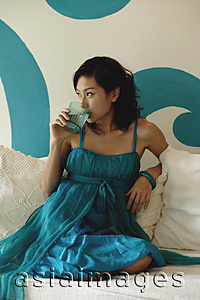 Asia Images Group - Woman sitting on daybed drinking water