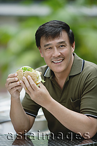 Asia Images Group - Man sitting outside eating a sandwich