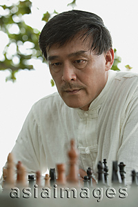 Asia Images Group - Man playing chess in park, deciding what move to make