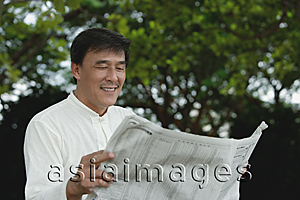 Asia Images Group - Man sitting in park reading newspaper