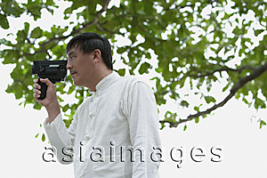 Asia Images Group - Man in park holding super 8 movie camera