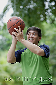 Asia Images Group - Man playing basketball in park