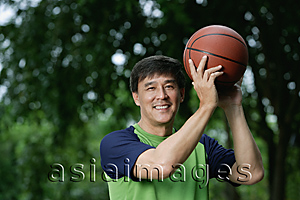 Asia Images Group - Man playing basketball in park, looking at camera, smiling