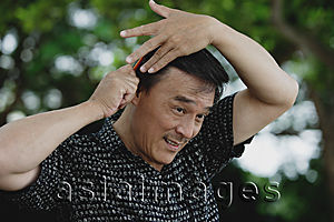Asia Images Group - Man combing hair in park