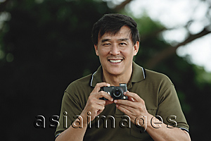 Asia Images Group - Man holding camera, taking picture, smiling
