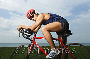 Asia Images Group - Man riding bike along ocean, looking at camera