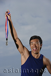 Asia Images Group - Man winning race, holding medal, smiling