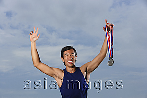 Asia Images Group - Man winning race, arms raised holding medals