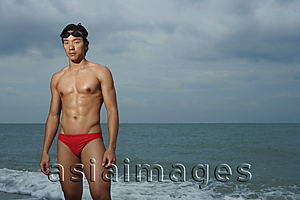 Asia Images Group - Muscled man wearing swim trunks by ocean, swimming