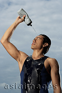 Asia Images Group - Man squeezing water bottle over face, cooling off after workout