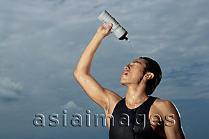 Asia Images Group - Man squeezing water bottle over face, cooling off after workout, hot