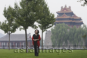 Asia Images Group - A woman stands in front of The Forbidden City, Beijing