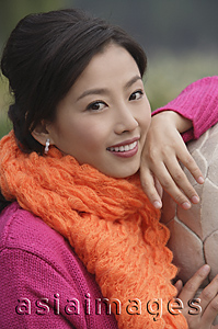 Asia Images Group - A woman looks at the camera as she leans on a stone wall