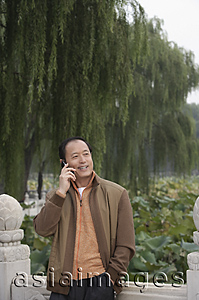 Asia Images Group - A man uses his cellphone as he stands outdoors