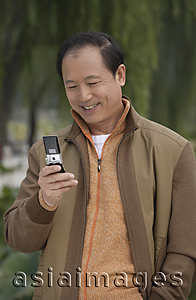 Asia Images Group - A man uses his cellphone as he stands outdoors