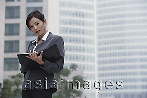 Asia Images Group - A businesswoman looks at the camera as she holds a folder