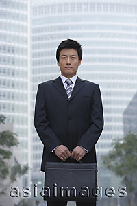 Asia Images Group - A businessman stands in the city with a briefcase