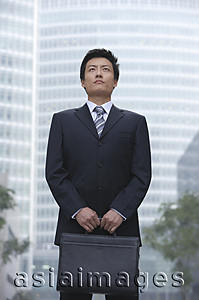 Asia Images Group - A businessman stands in the city with a briefcase