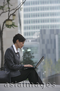 Asia Images Group - A businesswoman sits down and uses her laptop