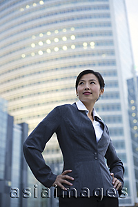 Asia Images Group - A businesswoman stands in front of a skyscraper
