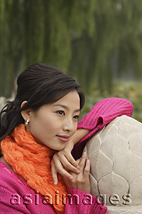 Asia Images Group - A woman looks into the distance as she leans on a stone wall