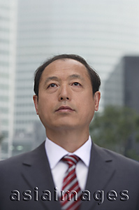 Asia Images Group - A businessman stands in front of a skyscraper