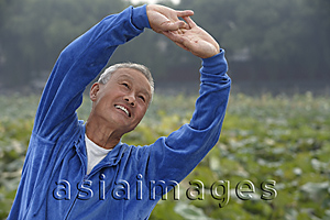 Asia Images Group - An old man in a blue tracksuit stretches