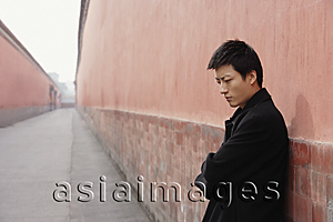 Asia Images Group - A man looks sad as he leans against a wall