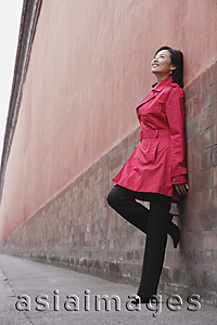Asia Images Group - A woman smiles as she leans against a wall