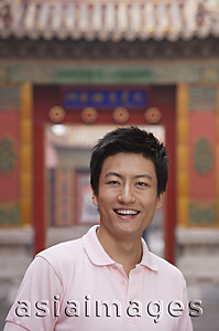 Asia Images Group - A man smiles at the camera as he stands in front of a doorway