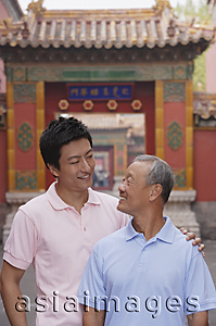 Asia Images Group - A grandfather and grandson stand in front of a tourist destination for a photo