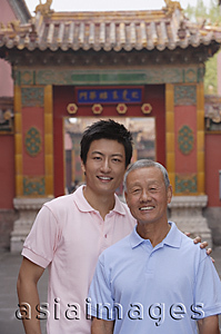 Asia Images Group - A grandfather and grandson look at the camera as they stand in front of a tourist destination for a photo