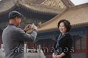 Asia Images Group - A woman smiles as she has her photo in front of The Forbidden City, Beijing