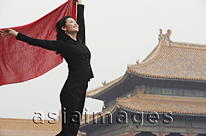 Asia Images Group - A woman holds a red shawl in the air in front of The Forbidden City, Beijing
