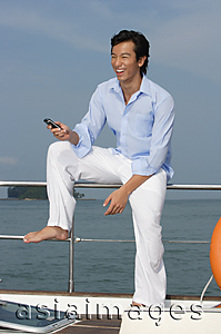 Asia Images Group - Man with mobile phone on yacht