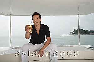 Asia Images Group - Man with glass on yacht, smiling at camera