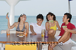 Asia Images Group - Young people playing cards on yacht