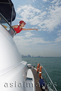 Asia Images Group - Young woman on yacht, pointing into distance