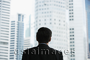 Asia Images Group - Businessman in the city, looking up at skyscrapers