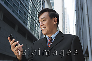 Asia Images Group - Businessman looking at mobile phone, smiling