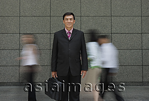 Asia Images Group - Businessman standing in crowd, looking at camera