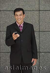 Asia Images Group - Businessman holding phone, looking at camera