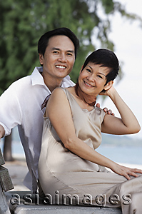 Asia Images Group - Mature couple at the beach sitting and smiling at camera