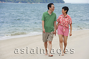 Asia Images Group - Mature couple walking at the beach looking at each other